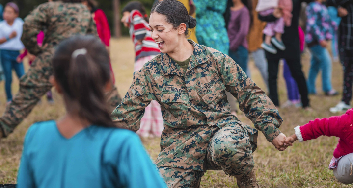 Women marine playing with children at a park.